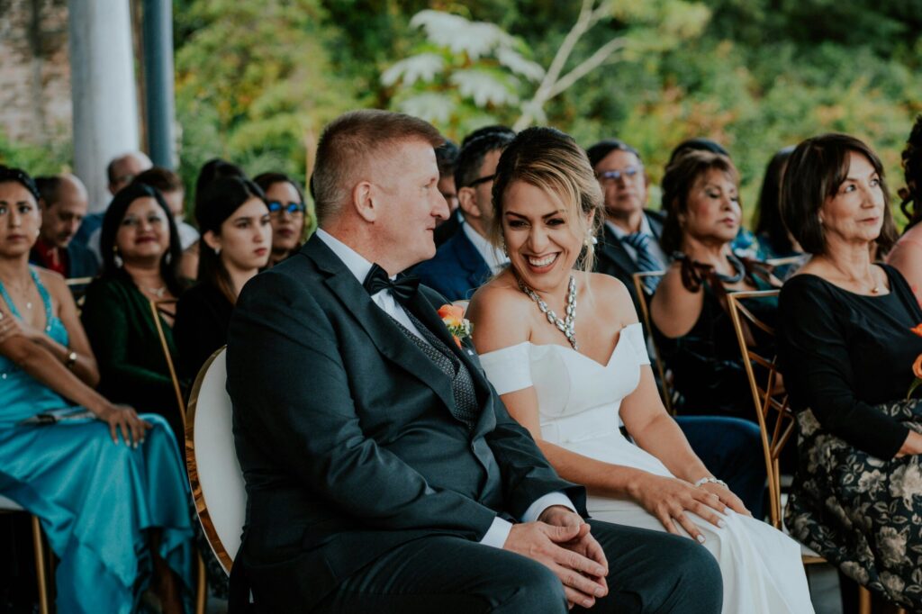 Bride and groom sharing a joyful moment during their wedding ceremony outdoors with guests.