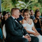Bride and groom sharing a joyful moment during their wedding ceremony outdoors with guests.