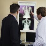 A doctor explains X-ray results to a patient in a clinical setting, highlighting healthcare communication.