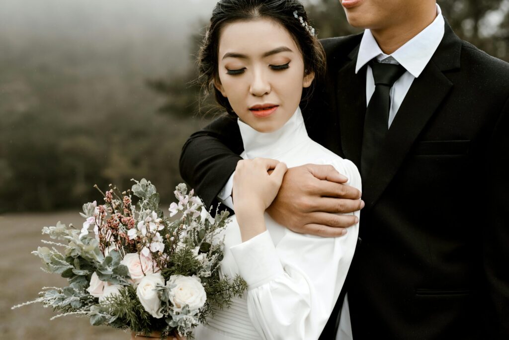 A romantic wedding portrait of a couple embracing outdoors, featuring a beautiful bouquet.