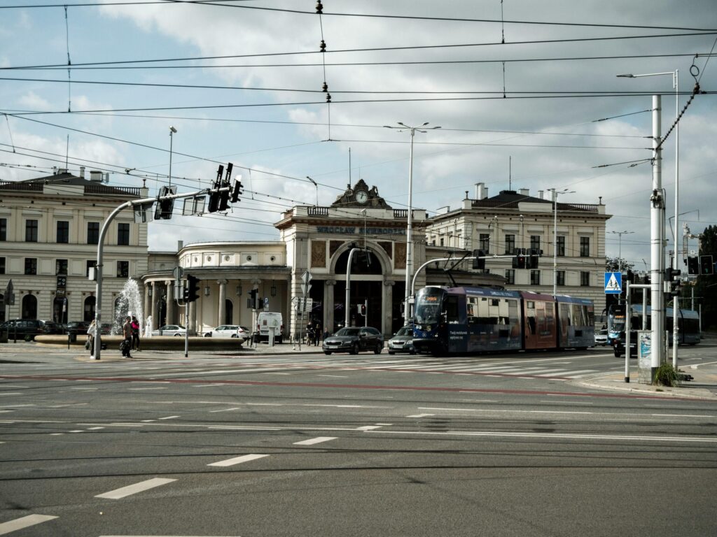 Tram passing in front of Wrocław's historic train station on a cloudy day.