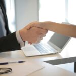 Close-up of a professional handshake over a laptop during a business meeting in an office.