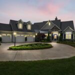 A modern suburban home at dusk, beautifully lit with exterior lights.