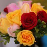 A colorful bouquet of roses with red, yellow, and pink blooms in a close-up shot.