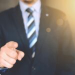 Confident businessman in a suit pointing forward, signifying leadership and focus.
