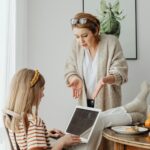 A mother scolds her teenage daughter absorbed in her laptop during breakfast at home.