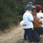 A loving mother with her two children exploring a forest path during the day.