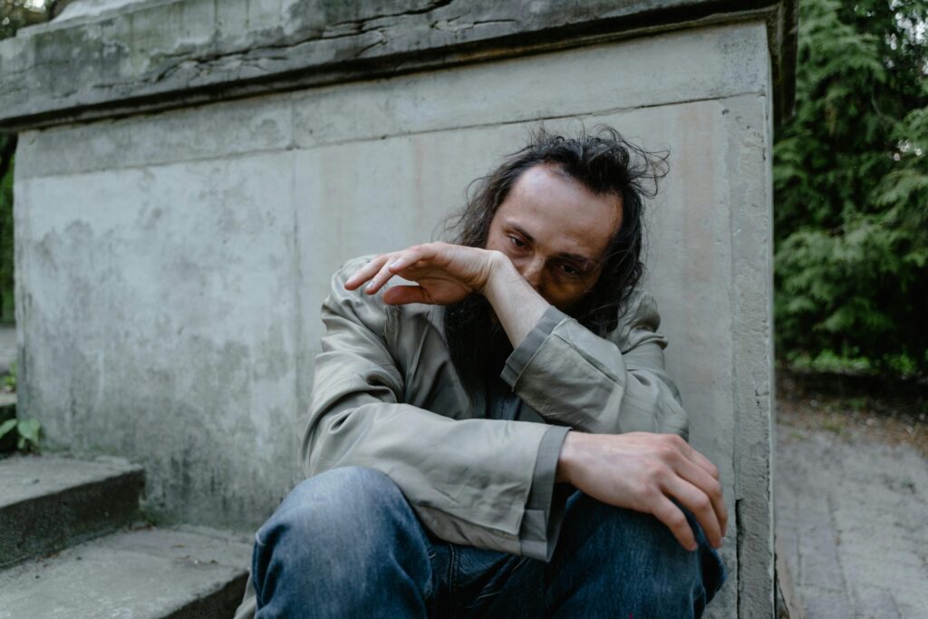 A pensive man sitting on concrete steps, conveying a sense of loneliness and despair.