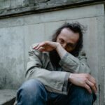 A pensive man sitting on concrete steps, conveying a sense of loneliness and despair.