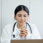 Young female doctor in white coat consulting online with stethoscope indoors.