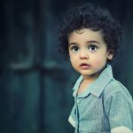 Charming portrait of a young boy with curly hair and striking eyes.