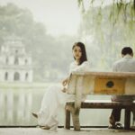 A couple sitting on a bench near Hanoi's iconic Turtle Tower, seemingly deep in thought.