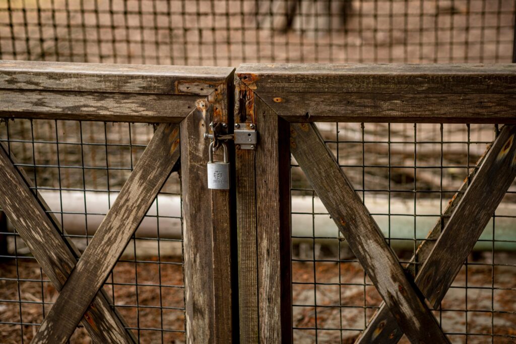 Close-up of a rustic wooden gate with a padlock, offering a secure outdoor setting.