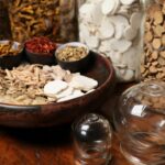 Close-up of herbal ingredients and glass jars used in traditional Chinese medicine therapy.