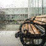 Rain-soaked window with a view of a bench outside in Fatih, Istanbul, Turkey.