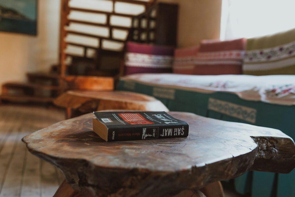 A cozy corner in a home featuring a book on a rustic wooden table and colorful decor.