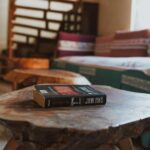 A cozy corner in a home featuring a book on a rustic wooden table and colorful decor.