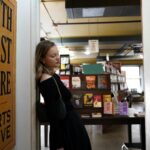 A young woman leaning on a wall inside The Last Bookstore in Los Angeles.