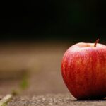 Close-up of a fresh red apple on a rustic background with blurred foreground.