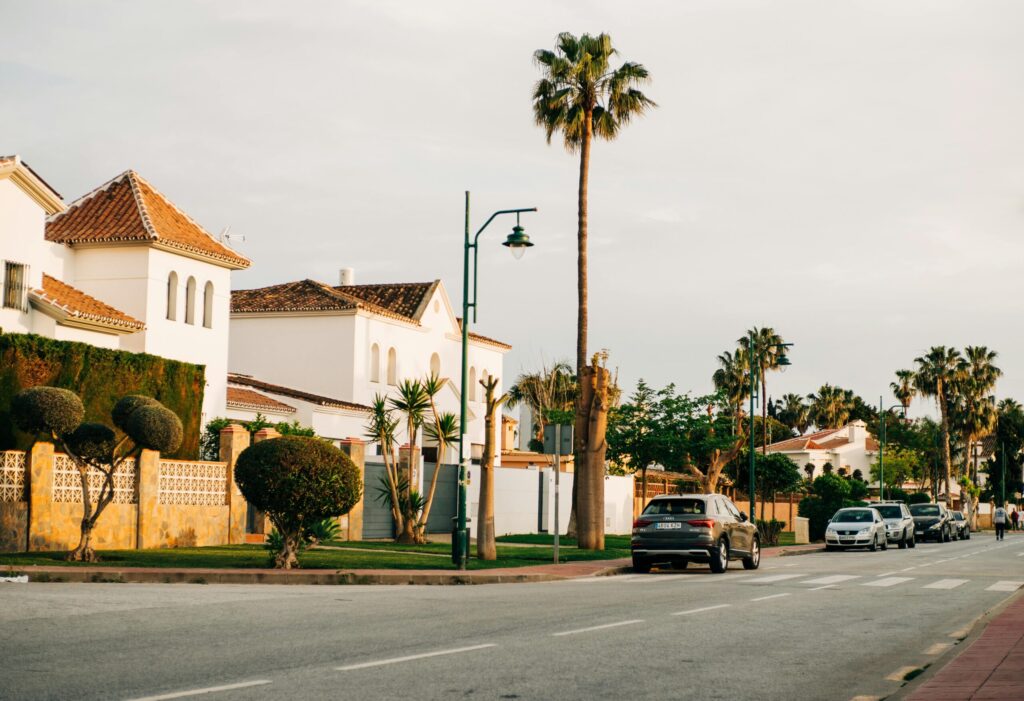 Picturesque street in Málaga, Spain featuring white houses and palm trees under a clear sky.