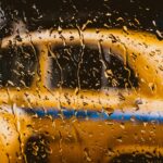 Blurred view of a yellow taxi through a rain-soaked window in Kolkata, India.