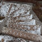 Wooden stairs with geometric patterns dusted in snow on a hiking trail.