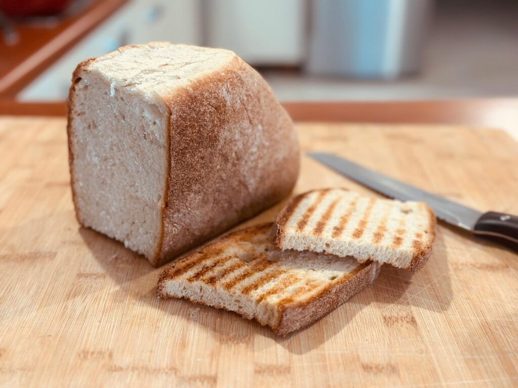 Rustic loaf of bread with sliced pieces on a wooden cutting board, ready to serve.