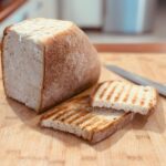 Rustic loaf of bread with sliced pieces on a wooden cutting board, ready to serve.