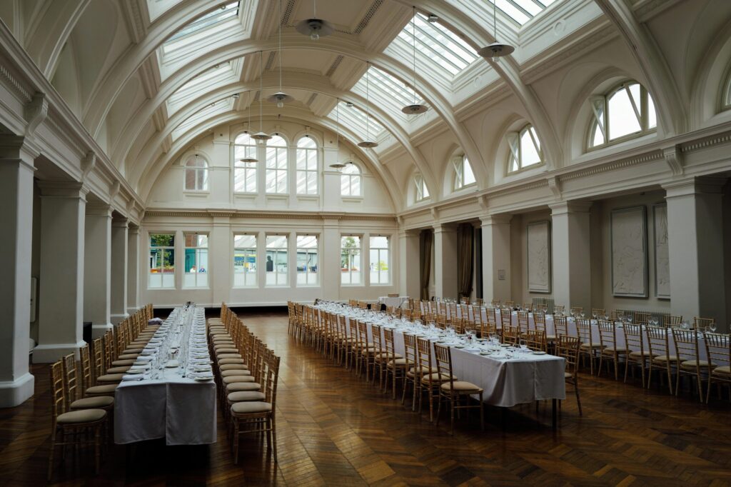 Spacious, elegant banquet hall with set tables and ornate ceiling, ready for events.