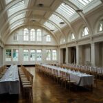 Spacious, elegant banquet hall with set tables and ornate ceiling, ready for events.