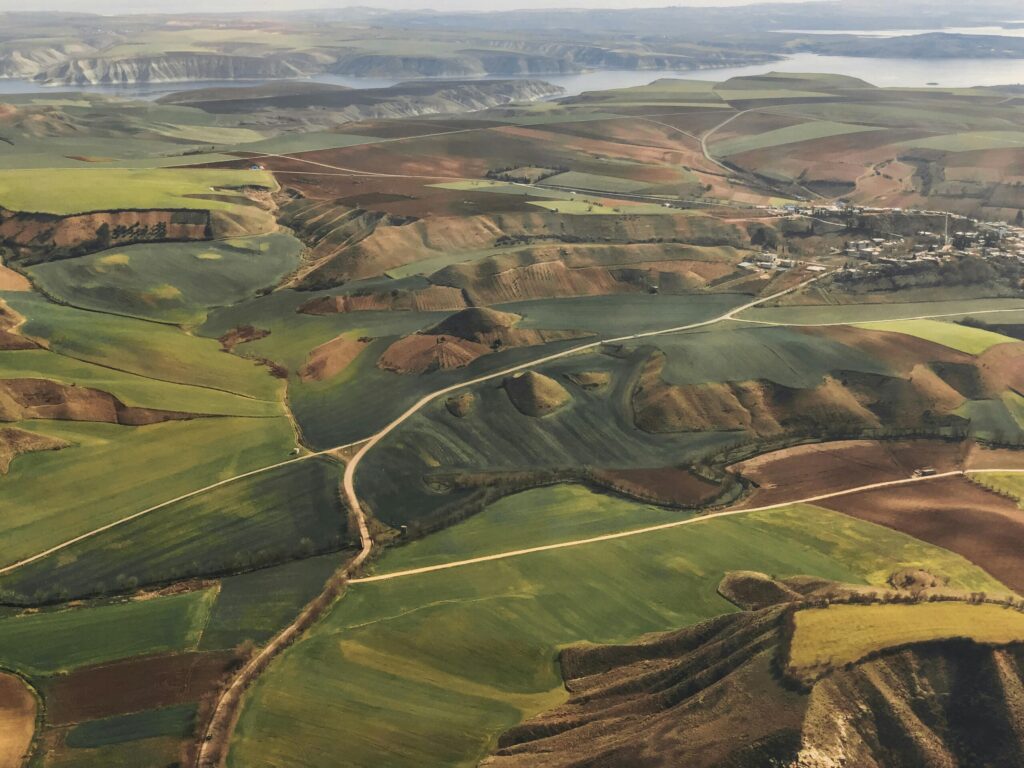An aerial view showcasing rolling hills and lush farmland under a clear sky.