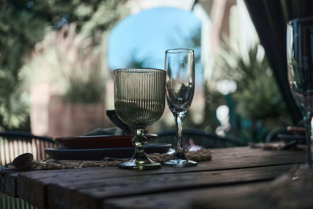 A serene outdoor dining setup featuring elegant glassware on a rustic wooden table.