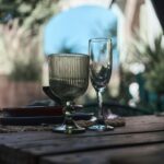 A serene outdoor dining setup featuring elegant glassware on a rustic wooden table.