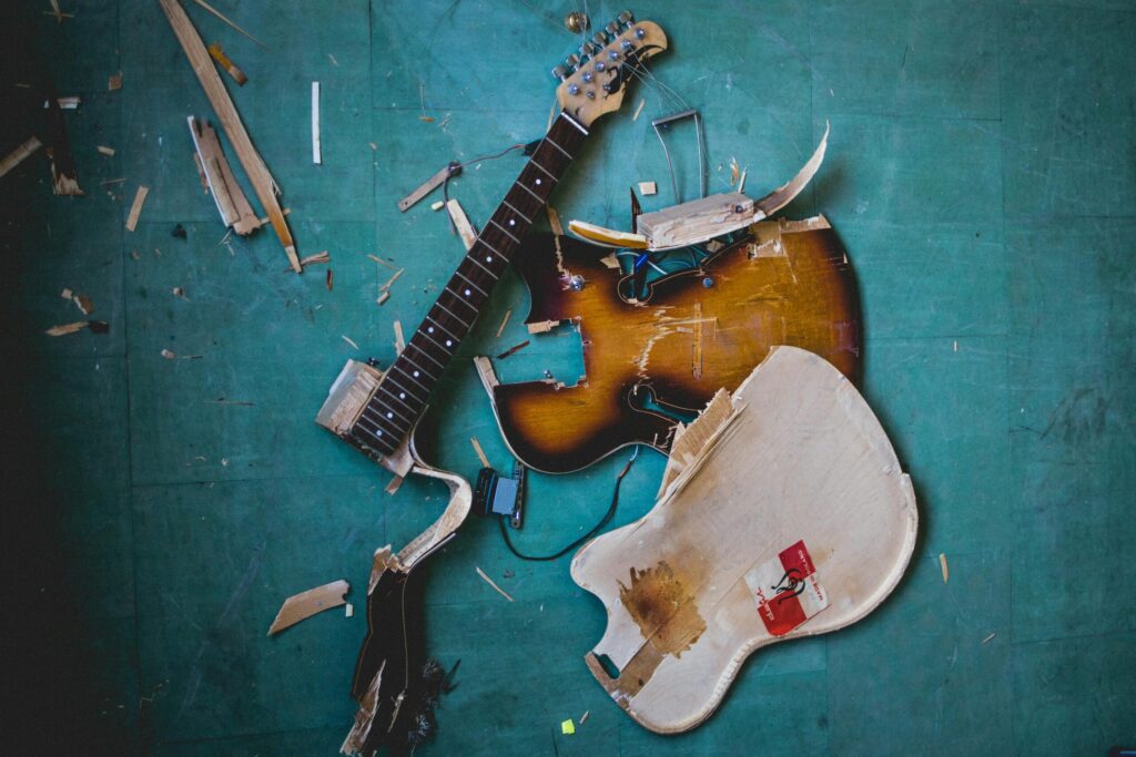 A dismantled electric guitar on a green floor, showcasing a chaotic musical scene.