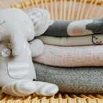 Cute knitted elephant toy and pastel blankets on a wicker chair, perfect for a cozy nursery.
