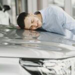 A man joyfully embracing a new car indoors, reflecting happiness and satisfaction.