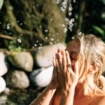 Woman enjoying a refreshing splash under natural spring water for relaxation.