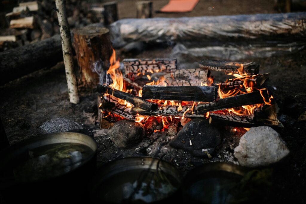 A warm campfire burning in a rustic outdoor setting with rocks and logs.