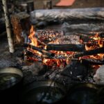 A warm campfire burning in a rustic outdoor setting with rocks and logs.