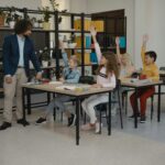 Children actively participating by raising hands during a class session, guided by their teacher.