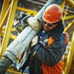 Construction worker in safety gear handling equipment on an active site.