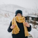 A woman wrapped in a warm scarf stands outdoors in a snowy Mongolian winter scene, showcasing cold weather fashion.
