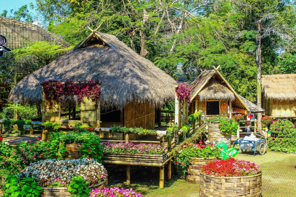Rustic huts nestled in a lush garden with colorful flowers creating a serene atmosphere.