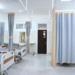 Spacious hospital ward in Surabaya, Indonesia with multiple medical beds and privacy curtains.