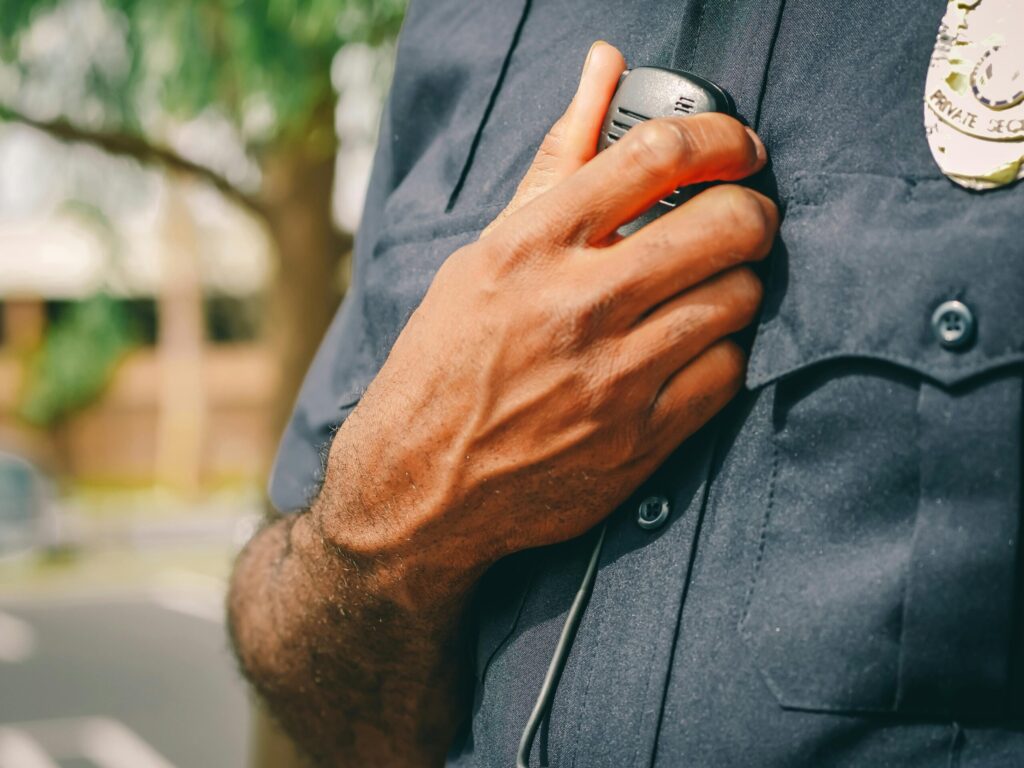 Close-up of police officer holding a radio outdoors, showcasing communication tools in law enforcement.
