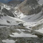 Breathtaking view of snow-covered mountains and a remote cabin in the Dolomites, Italy.