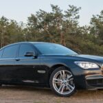 Luxurious black BMW sedan parked outdoors with forest backdrop. Ideal for automotive themes.