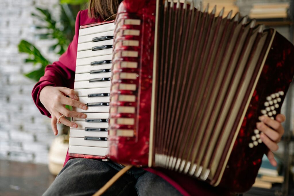 Musician's hands playing an accordion indoors with focus on keys and buttons.