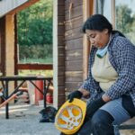 A construction worker in a plaid shirt and hard hat takes a break outdoors, reflecting on the day.