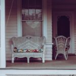 Cozy vintage-style front porch with white wicker chairs and floral cushions.